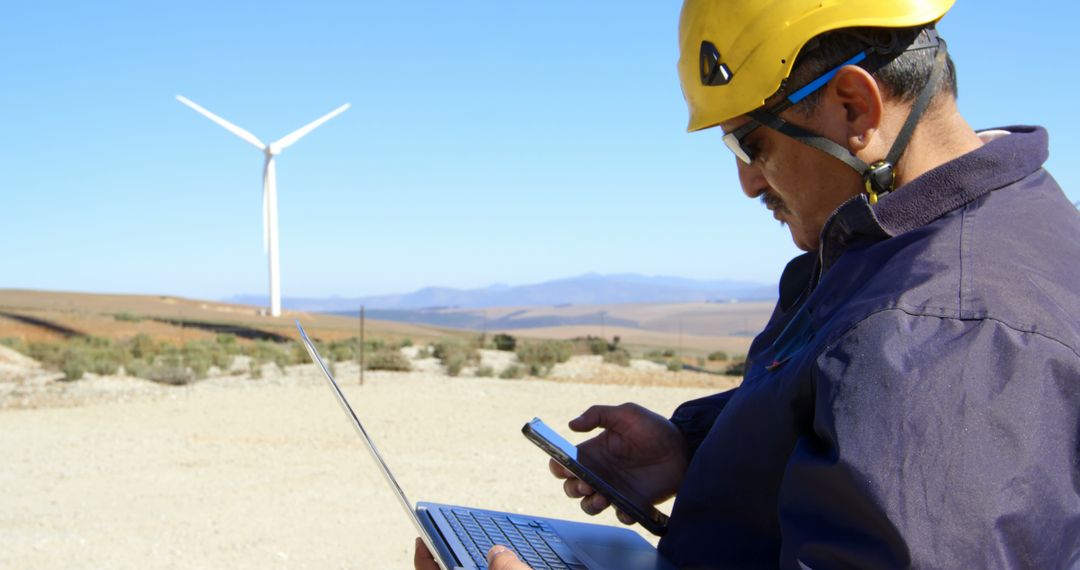 Engineer Monitoring Wind Farm with Laptop and Mobile Device - Free Images, Stock Photos and Pictures on Pikwizard.com