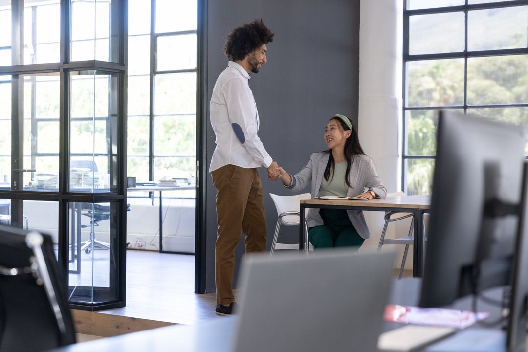 Diverse Coworkers Shaking Hands in Modern Open Office Space