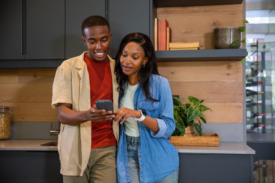 Smiling Couple Enjoying Smartphone Together in Modern Kitchen