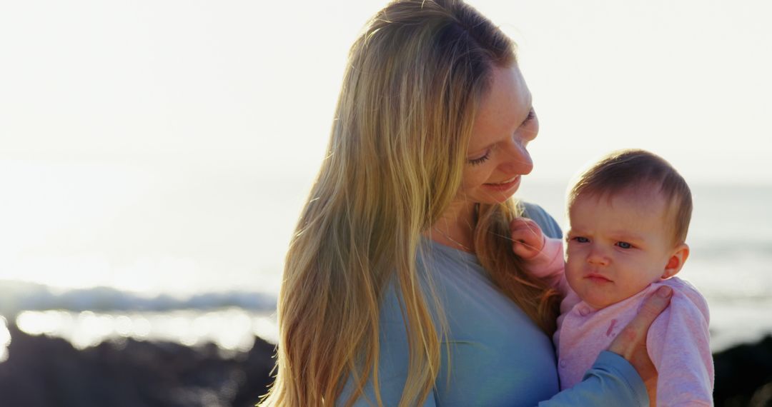 Mother Holding Baby by Sea with Warm Sunlight - Free Images, Stock Photos and Pictures on Pikwizard.com