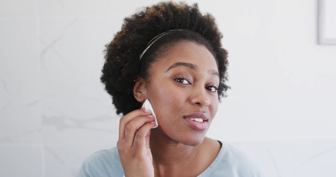 Young Black woman maintaining skincare routine in bathroom - Free Images, Stock Photos and Pictures on Pikwizard.com