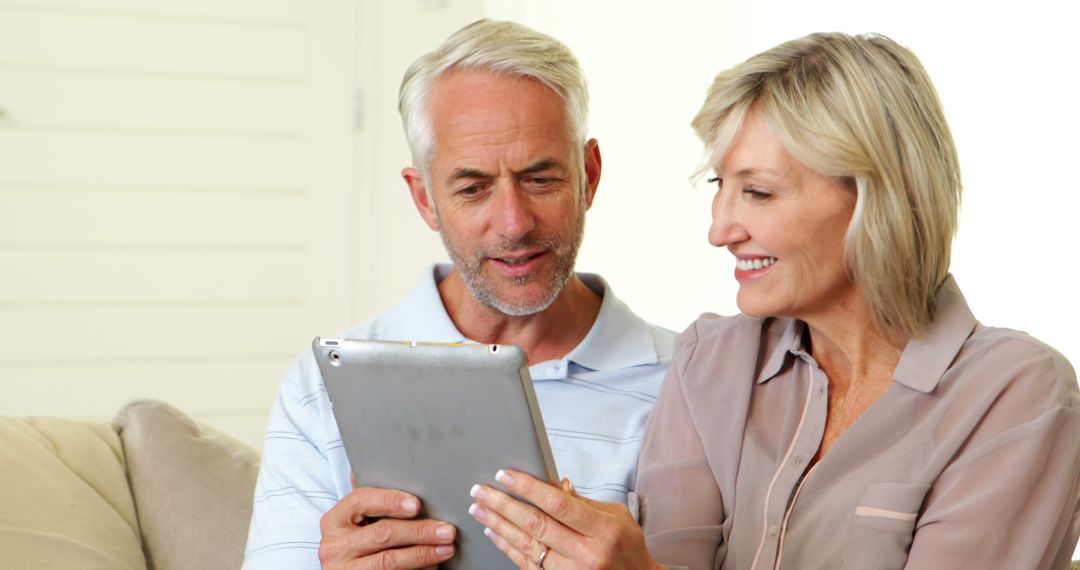 Senior Couple Enjoying Tablet Browsing on Comfortable Couch