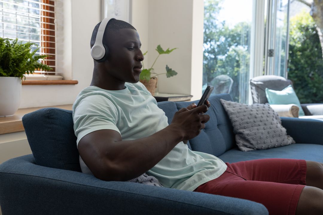 Relaxed Man Using Smartphone with Headphones at Home