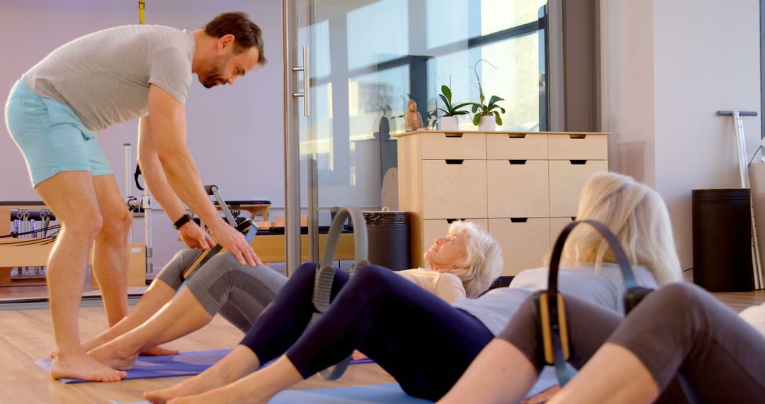 Senior women in pilates class with male instructor guiding - Free Images, Stock Photos and Pictures on Pikwizard.com