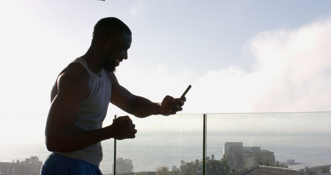 Man Celebrating Achievement on Balcony with Serene Ocean View