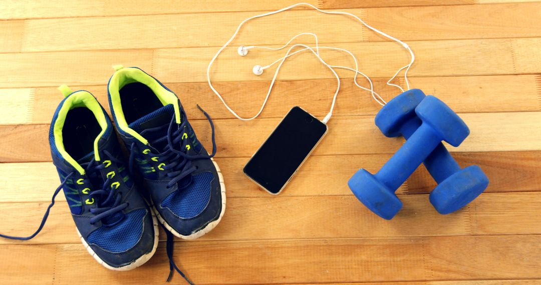 Fitness Essentials on Wooden Floor: Sneakers, Mobile Phone, Dumbbells - Free Images, Stock Photos and Pictures on Pikwizard.com