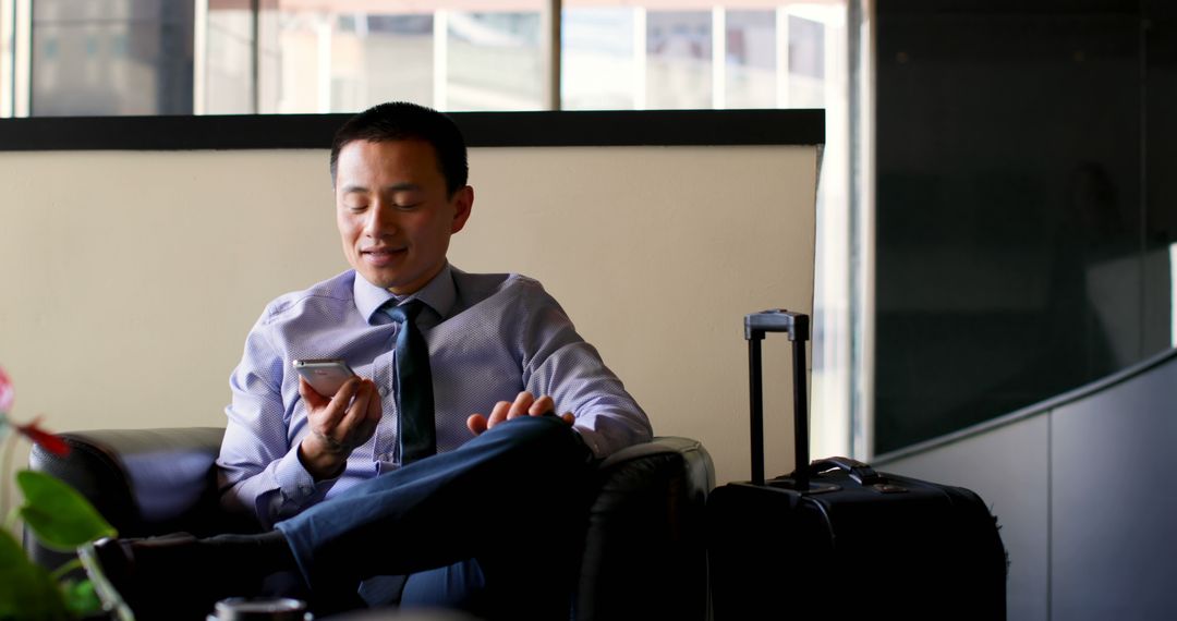 Businessman Sitting with Suitcase, Using Smartphone in Modern Office - Free Images, Stock Photos and Pictures on Pikwizard.com