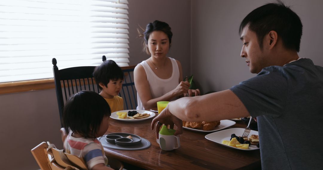 Asian Family Enjoying Meal Together with a Playful Toddler