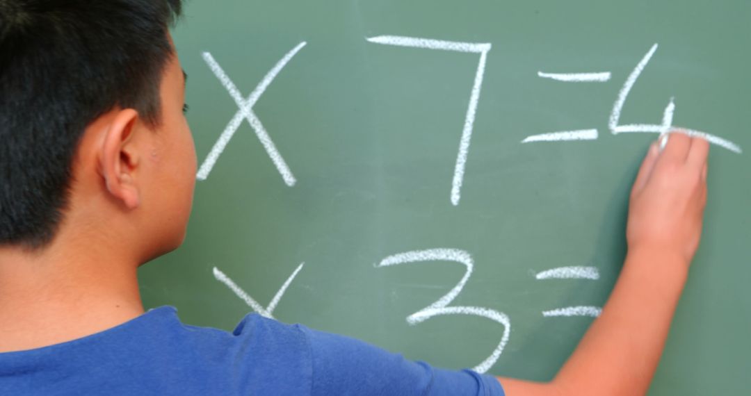 Schoolboy Solving Multiplication Problem on Chalkboard