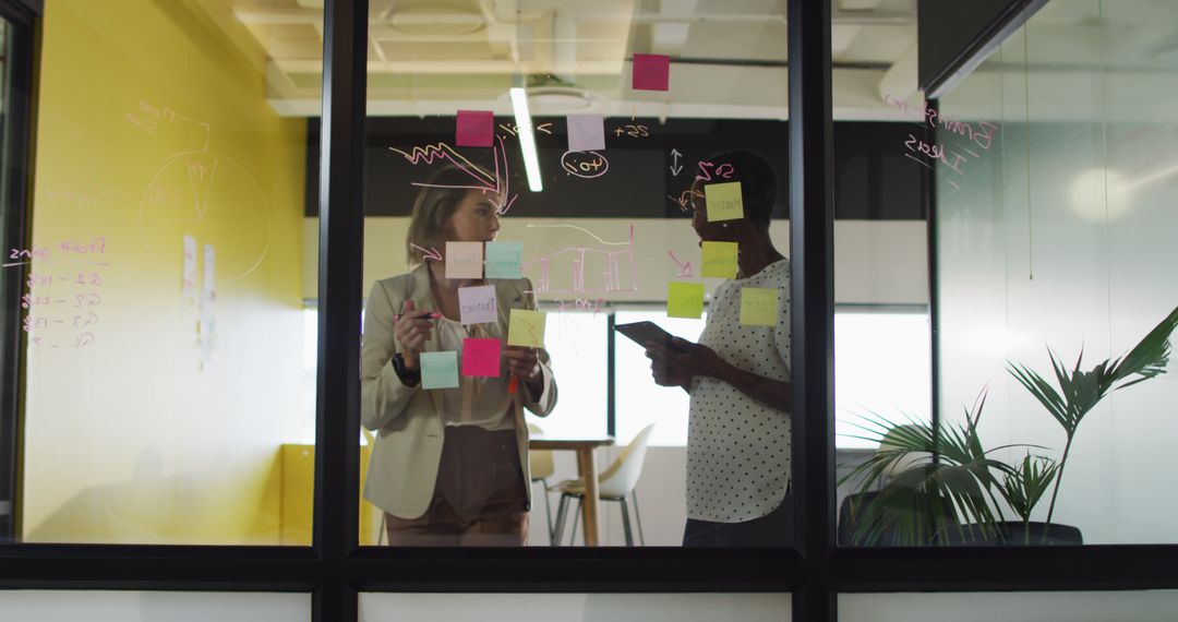 Business Colleagues Having Strategy Meeting with Sticky Notes on Glass Wall - Free Images, Stock Photos and Pictures on Pikwizard.com