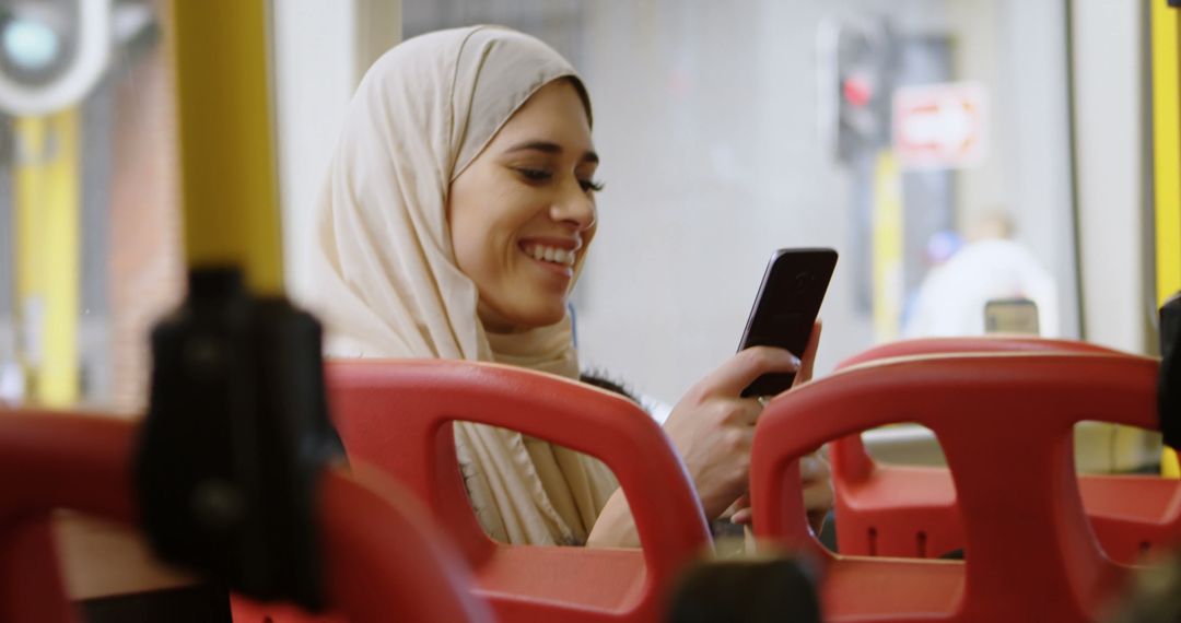 Smiling Muslim Woman Using Smartphone on Public Bus - Free Images, Stock Photos and Pictures on Pikwizard.com