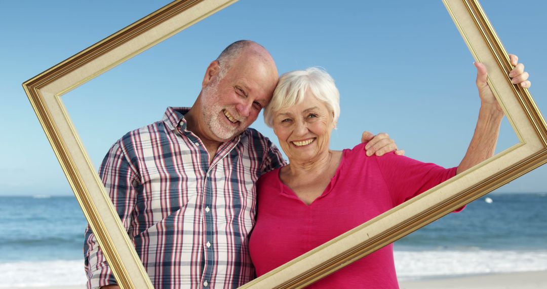 Happy Senior Couple Holding Picture Frame on Beach - Free Images, Stock Photos and Pictures on Pikwizard.com