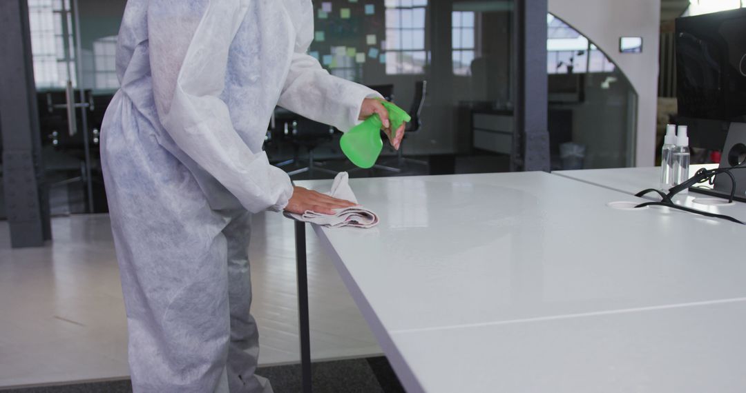 Person Cleaning Office Desk with Disinfectant Spray in Protective Gear - Free Images, Stock Photos and Pictures on Pikwizard.com