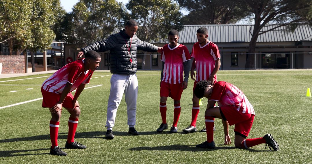 Coach Supporting Tired Young Soccer Players on Field