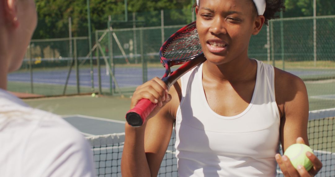 Image of happy african american female tennis player holding racket and talking with friend - Free Images, Stock Photos and Pictures on Pikwizard.com
