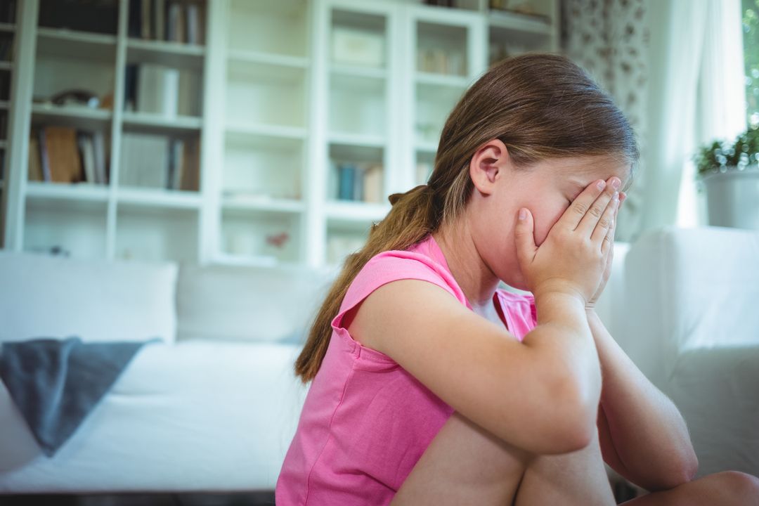 Lonely Child Hugging Knees in Living Room Interior