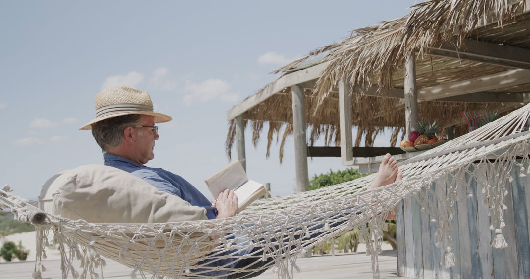 Senior Man Relaxing in Hammock by Beachside Cabana, Reading Book - Free Images, Stock Photos and Pictures on Pikwizard.com