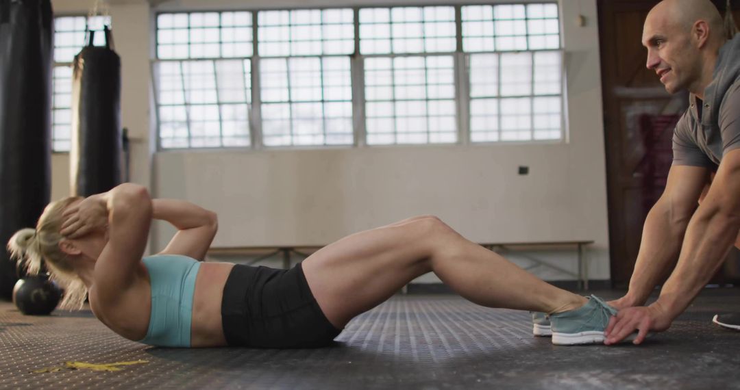Woman Performing Sit-Ups with Trainer Support in Gym