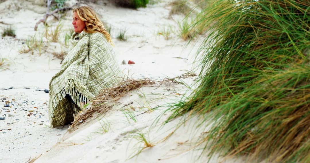 Woman Relaxing by Coastal Sand Dunes Wrapped in Blanket - Free Images, Stock Photos and Pictures on Pikwizard.com