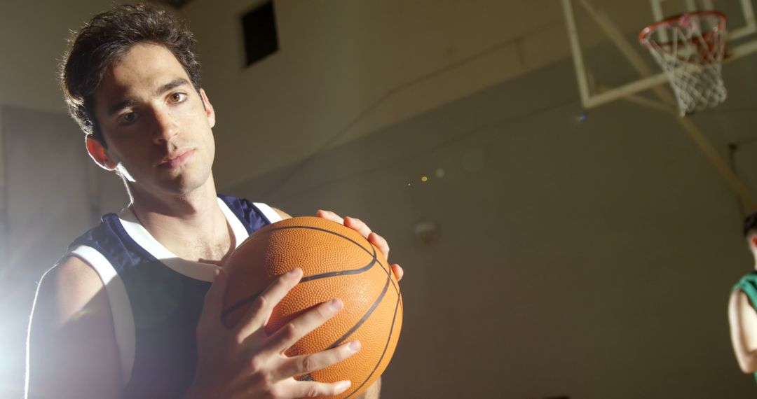 Young Basketball Player on Indoor Court Holding Ball, Focused Expression - Free Images, Stock Photos and Pictures on Pikwizard.com