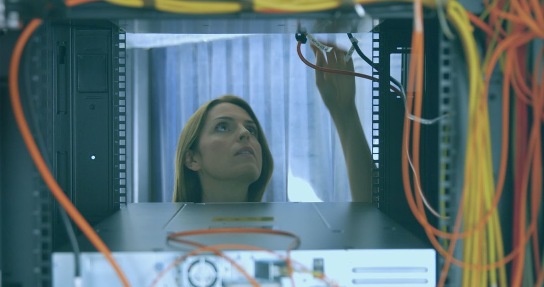 Female Engineer Examining Cables in a Data Center