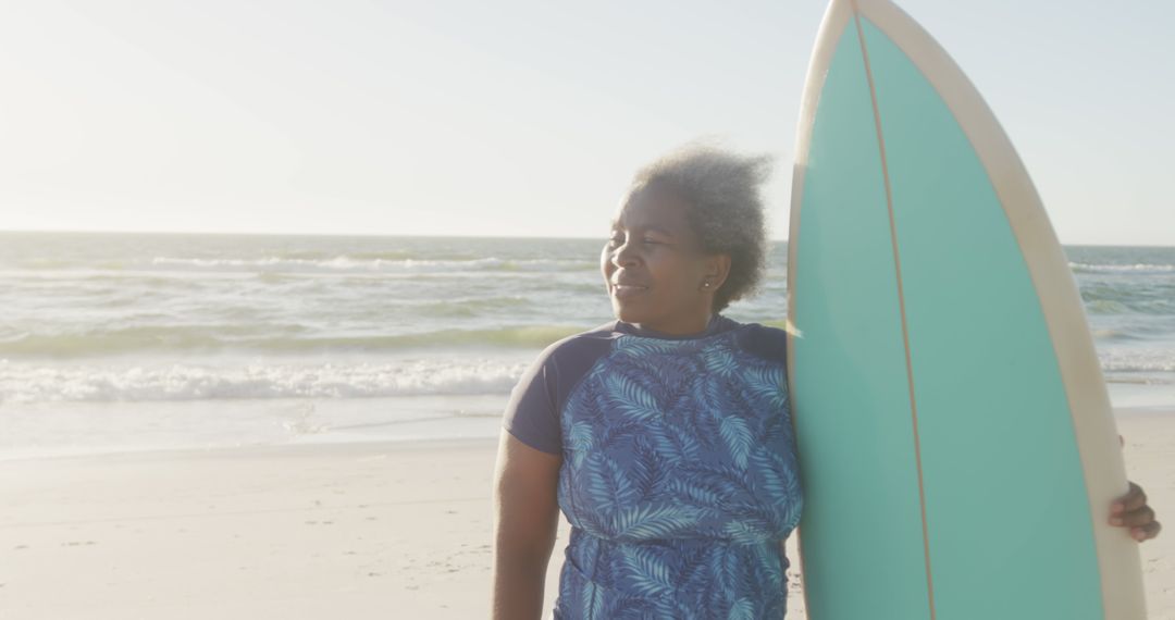 Senior Woman Holding Surfboard at Beach on Sunny Day - Free Images, Stock Photos and Pictures on Pikwizard.com