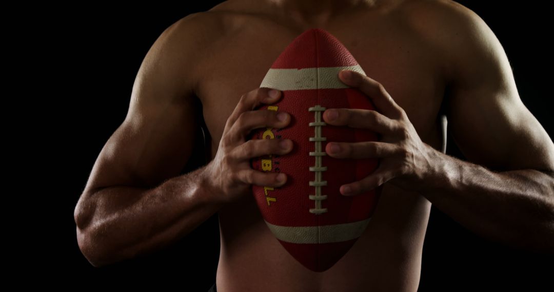 Muscular Athlete Holding Football Against Dark Background - Free Images, Stock Photos and Pictures on Pikwizard.com