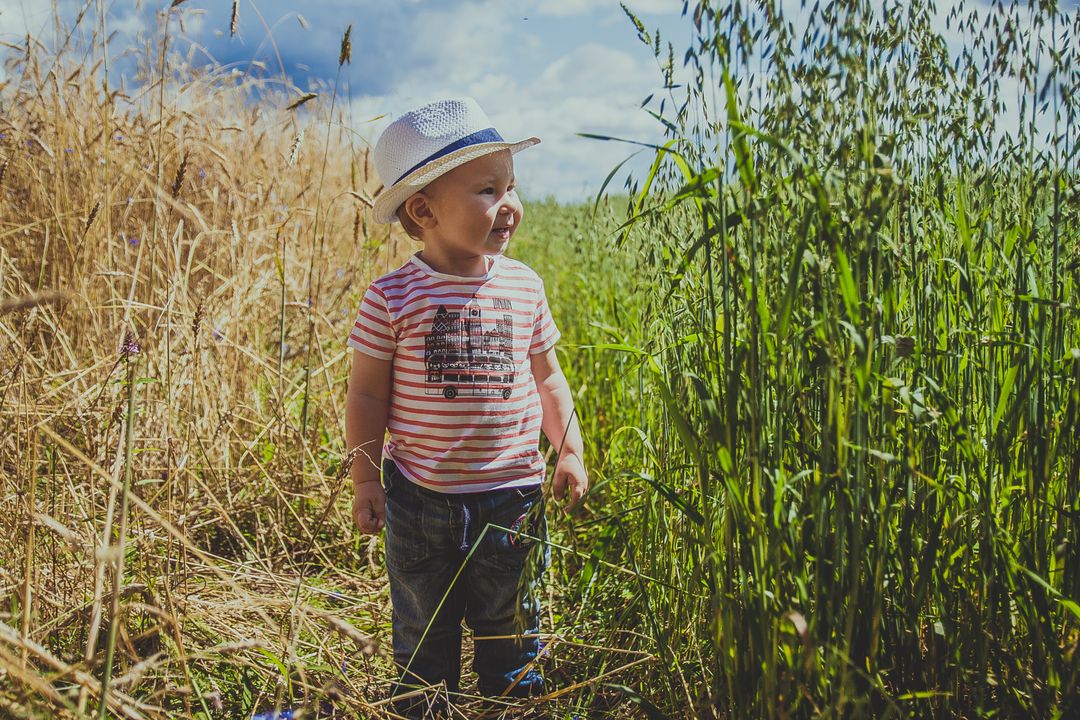 Happy Toddler in Straw Hat Exploring Green Field - Free Images, Stock Photos and Pictures on Pikwizard.com