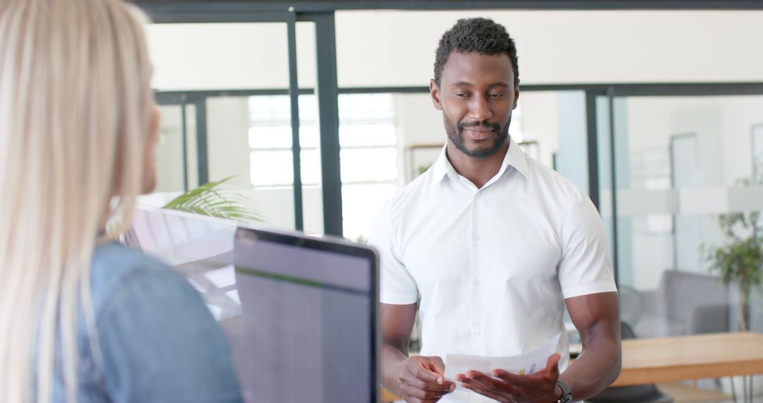 Diverse Colleagues Discussing Work Over Laptop in Modern Office