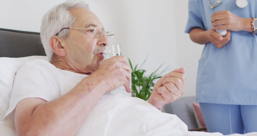 Elderly Man Drinking Water in Hospital Bed with Nurse Nearby - Free Images, Stock Photos and Pictures on Pikwizard.com