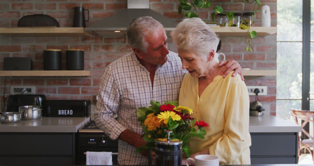 Senior Couple Embracing with Flowers in Modern Kitchen - Free Images, Stock Photos and Pictures on Pikwizard.com