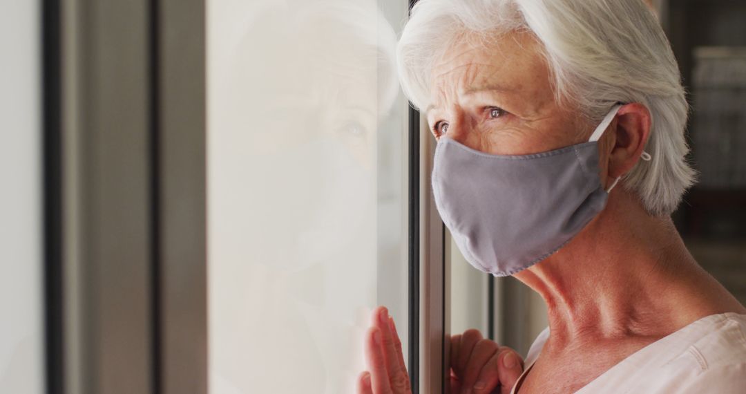 Elderly Woman Wearing Face Mask Looking Out Window in Contemplation - Free Images, Stock Photos and Pictures on Pikwizard.com