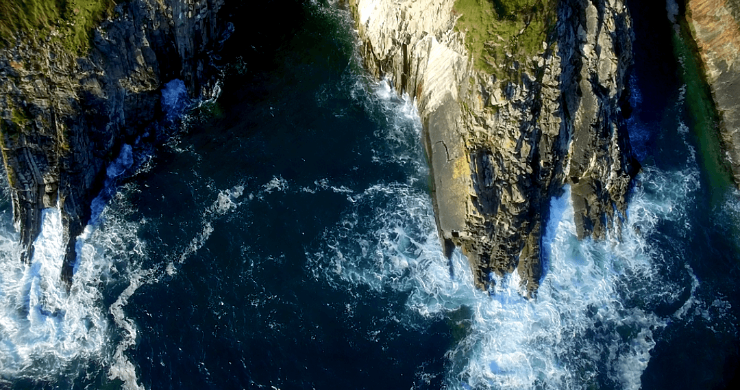 Stunning Aerial View of Cliffs Overlooking Strong Sea Waves With Transparent Foam