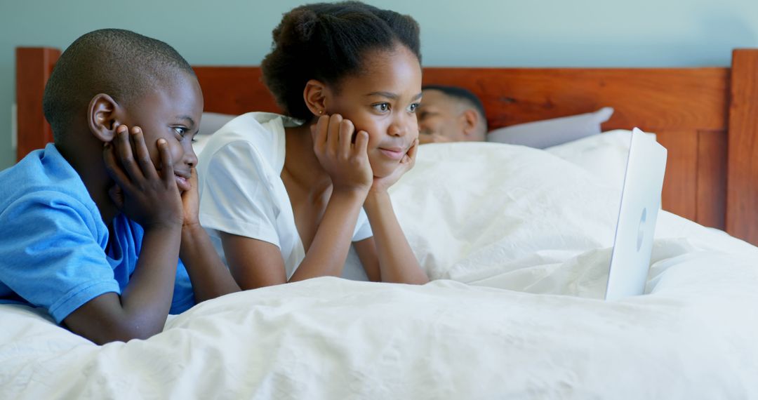 Two African American Siblings Watching Tablet Together in Bed - Free Images, Stock Photos and Pictures on Pikwizard.com