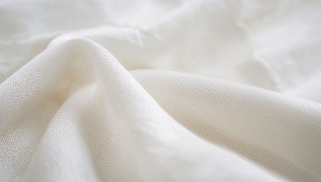 Showcasing cream-white woven fabric with soft folds and fine weave texture for textiles
