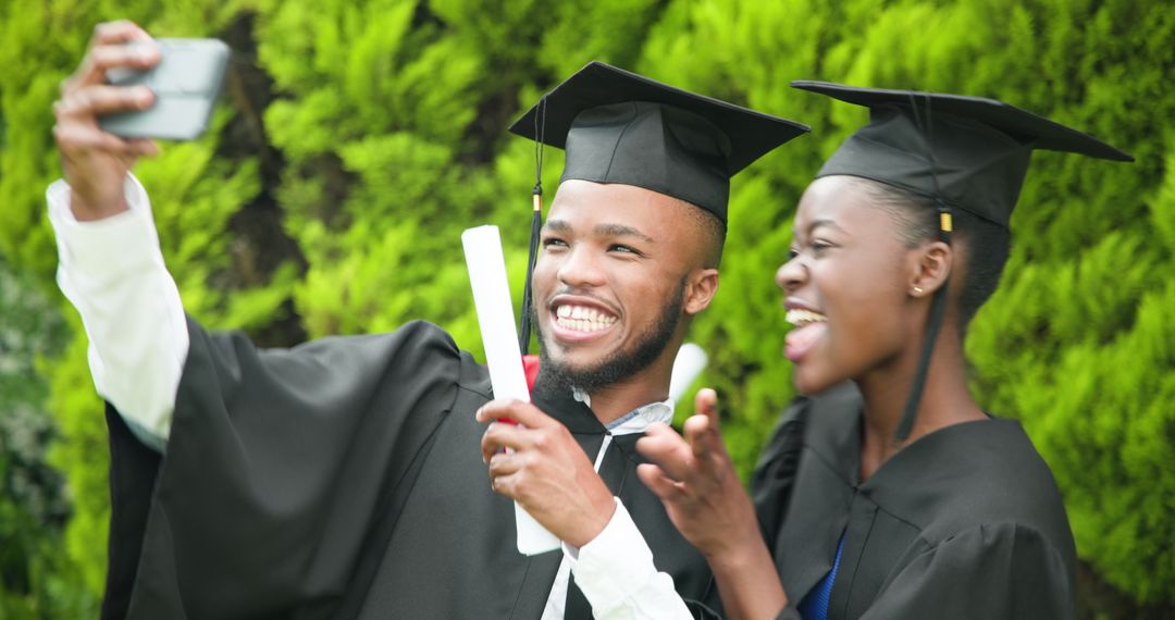 Joyful Graduates Capturing Memories with Selfie Outdoors