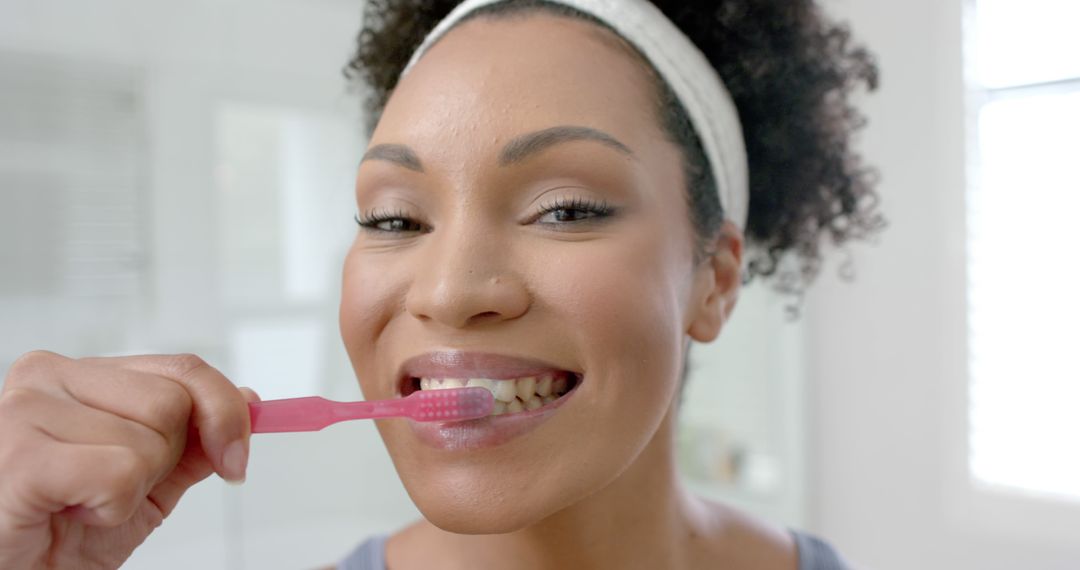 Woman Brushing Teeth with Pink Toothbrush in Bathroom - Free Images, Stock Photos and Pictures on Pikwizard.com