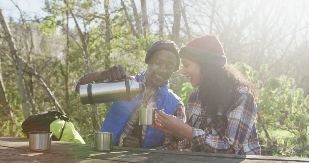 Couple Enjoying Hot Drink Outdoors in Sunlit Forest - Free Images, Stock Photos and Pictures on Pikwizard.com