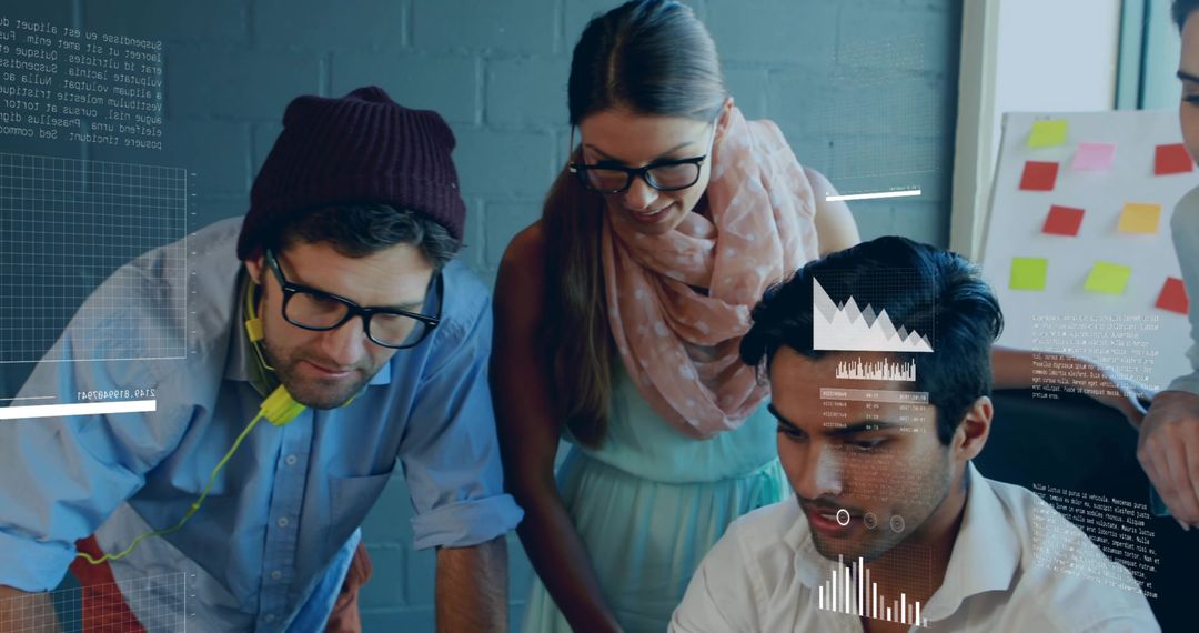 Creative team collaborating around laptop analyzing data visualizations in modern office