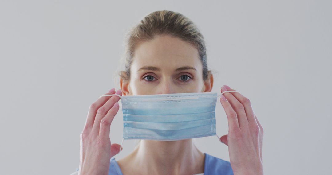 Healthcare Worker Adjusting Face Mask with Focused Expression - Free Images, Stock Photos and Pictures on Pikwizard.com