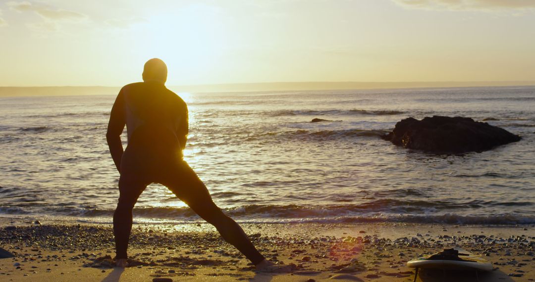 Surfer Stretching on Beach at Sunrise by Ocean - Free Images, Stock Photos and Pictures on Pikwizard.com