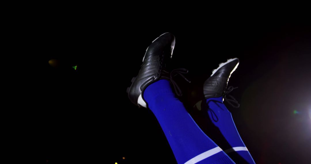 Soccer Player's Feet in Mid-Air with Blue Socks and Black Soccer Cleats - Free Images, Stock Photos and Pictures on Pikwizard.com