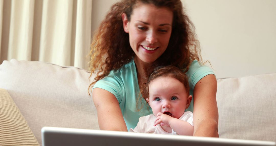 Mother Working Remotely with Baby in Arms on Couch - Free Images, Stock Photos and Pictures on Pikwizard.com