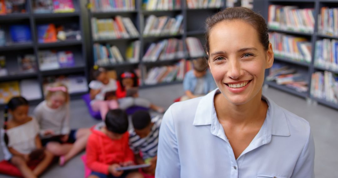 Smiling Teacher Standing in Library with Children Studying Behind