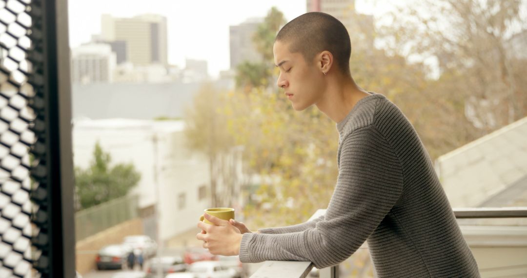 Young Man Relaxing on Balcony with Coffee Overlooking Cityscape - Free Images, Stock Photos and Pictures on Pikwizard.com