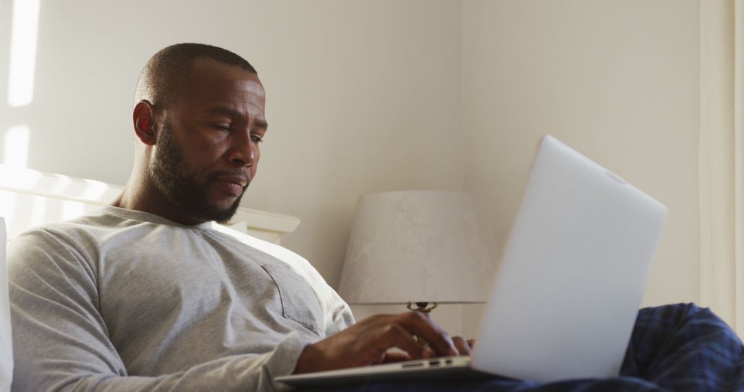 Man Relaxing on Bed Using Laptop Computer in Bright Room - Free Images, Stock Photos and Pictures on Pikwizard.com