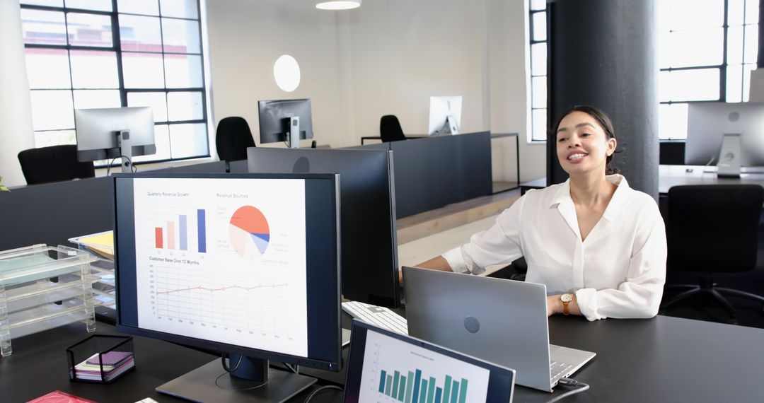 Smiling Businesswoman in Modern Office with Laptops and Analytics