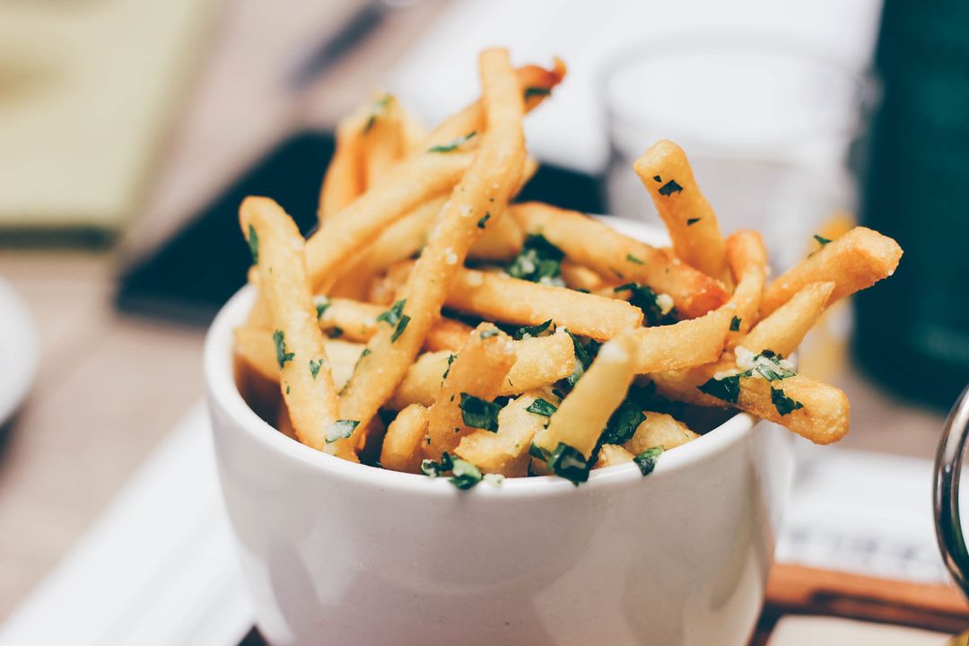 Crispy Garlic Herb French Fries in White Bowl Garnished with Chopped Parsley