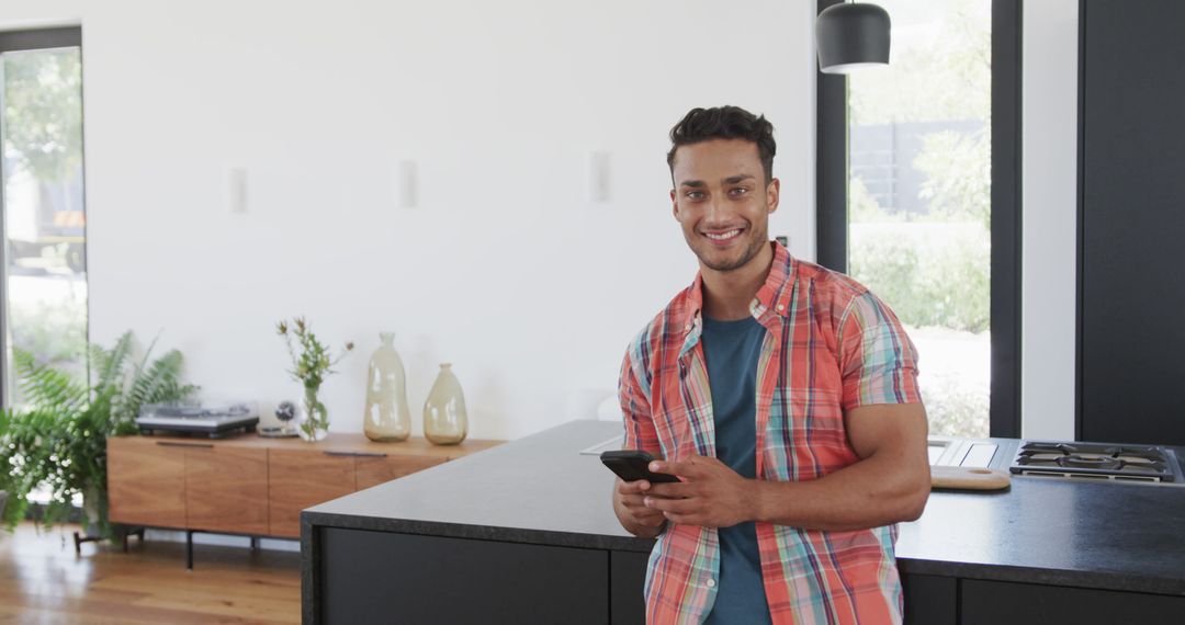 Cheerful Young Man Using Smartphone in Modern Kitchen - Free Images, Stock Photos and Pictures on Pikwizard.com