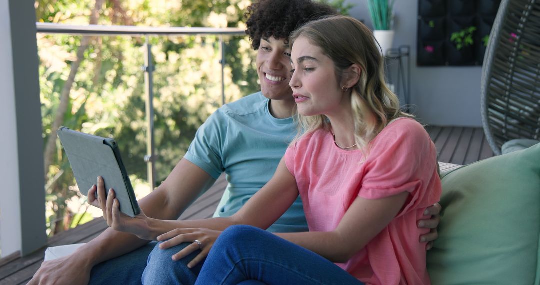 Couple Video Chatting on Tablet While Relaxing on Balcony